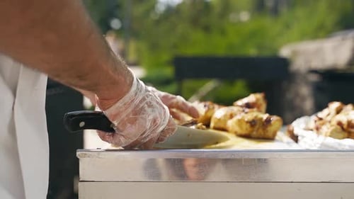 Chef Cuts Grilled Chicken Outdoors for Serving