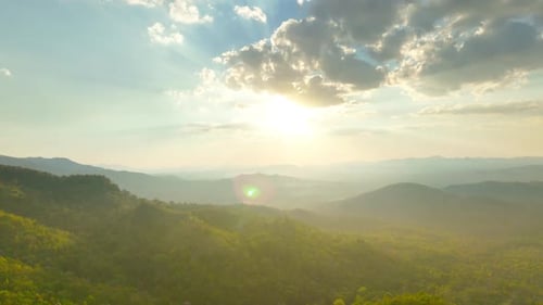 Golden Sunbeams Piercing Through Clouds Over Rolling Green Mountain Ridges