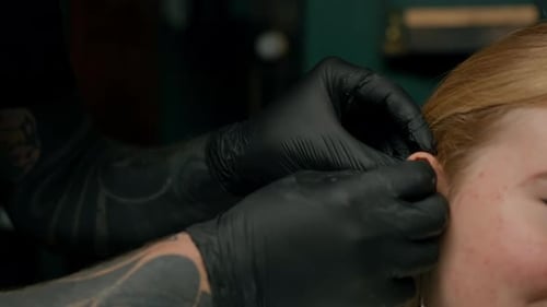 Piercing studio interior - piercing master makes a piercing to a girl, ear piercing