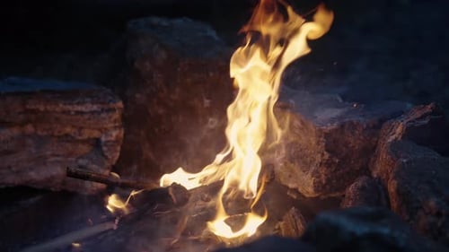 Bonfire burning bright in Slow Motion, peaceful orange campfire with sparks surrounded by stones, Cl