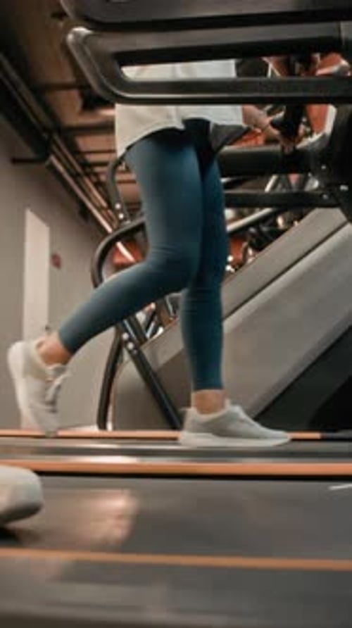 Vertical of Legs of Woman Doing Cardio Workout on Treadmill in Gym