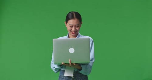 An Asian Business Woman Using Laptop Computer On Green Screen Background In The Studio