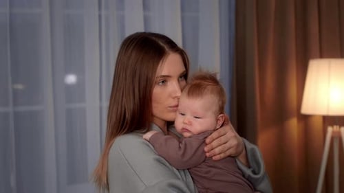 Woman Holding Adorable Infant in Cozy Home Setting