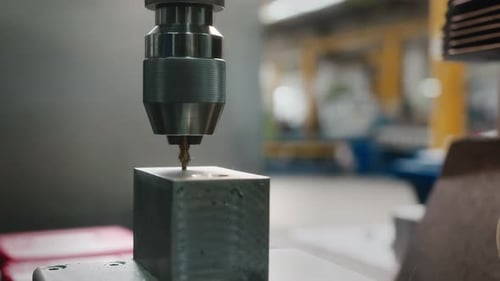 Ein kurzer Bohrer, der in einer Autofabrik an einem Metallblock arbeitet