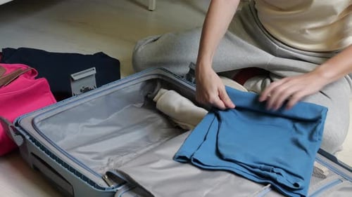 Woman Packing Clothes into Suitcase for Travel