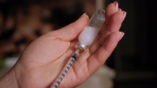 Closeup of a Woman Dialling the Right Dose of Insulin Into a Syringe