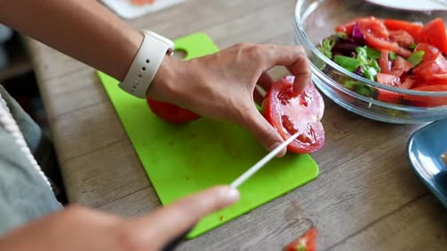 Woman Cuts Tomato For Salad at Home