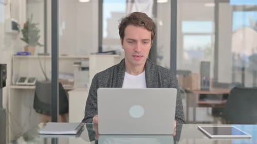 Mann mittleren Alters begeistert vom Online-Handel auf dem Laptop im Büro