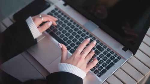 Nahaufnahme von Händen, die mit dem Smartphone auf einem Holztisch tippen