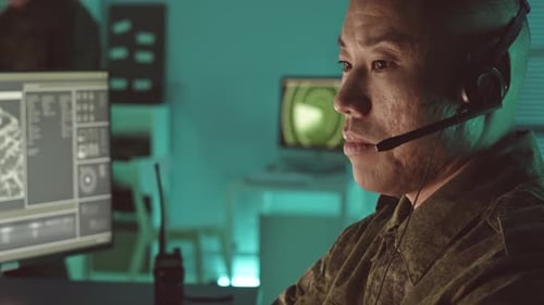 Soldier wearing headset looking at computer monitors