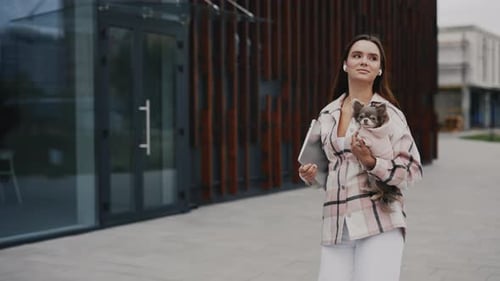 Caucasian Woman on a Walk with a Small Chihuahua Holding Him on the Hands Holding the Laptop The Pet