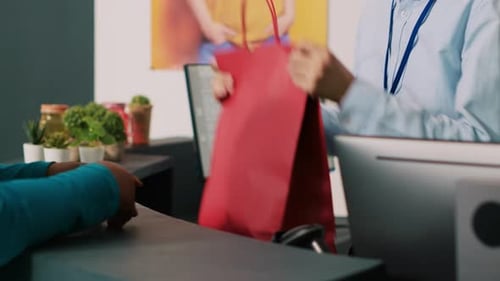 Cashier Hands Bag and Payment Terminal to Customer