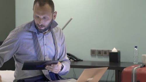 Focused businessman multitasking with technology in a hotel room at night