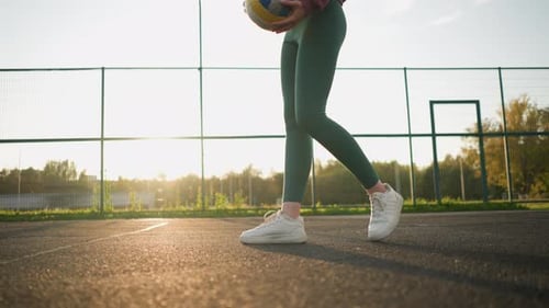 Athlete Bouncing Volleyball in Sunlit Court with Low Angle View