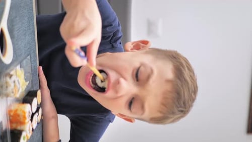 Boy Eating Sushi with Chopsticks at Home
