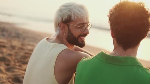 De perto, casal homossexual apaixonado passa tempo juntos sentados na praia ao nascer do sol