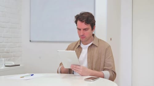 Frustrated Man Using Tablet at Home Office Desk