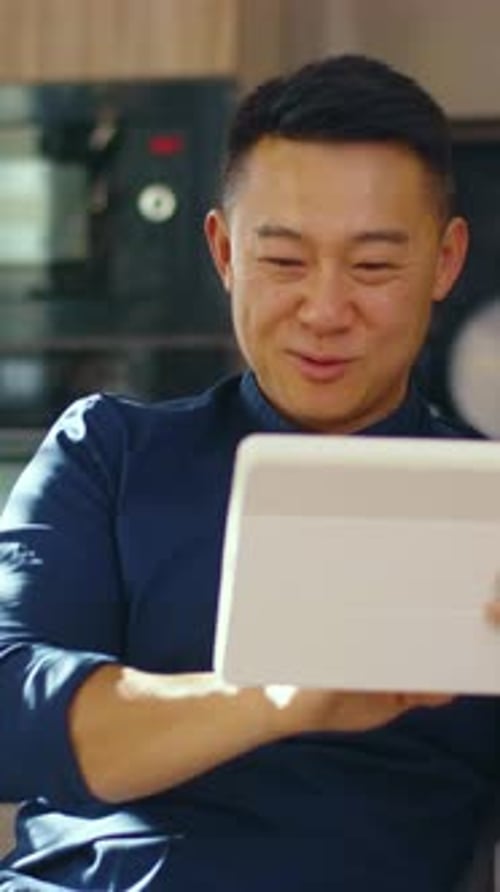 Smiling Man Using Tablet Device at Home