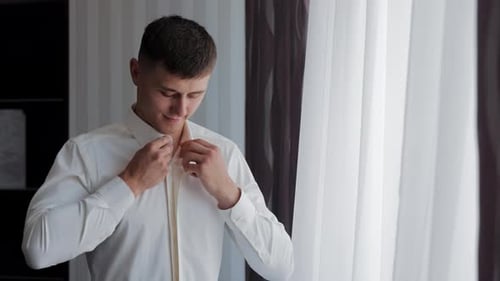 Handsome Man Buttons a White Shirt Before Wedding