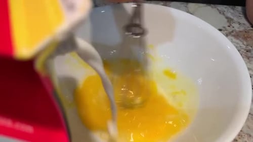 Mixing Eggs and Milk in Bowl with Whisk