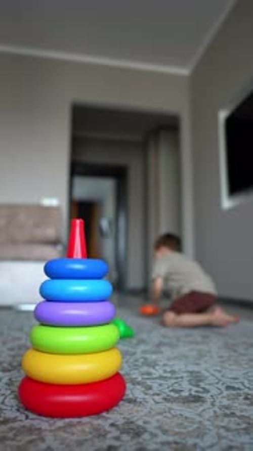 Un
niño caucásico activo construye una pirámide. Un precioso bebé juega alegremente en casa. Vídeo vertical.