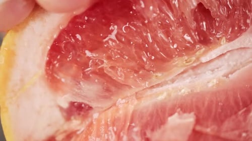 Slow Motion Footage of Person Squeezing a Grapefruit Close Up View of Juicy Red Orange Fruit Making