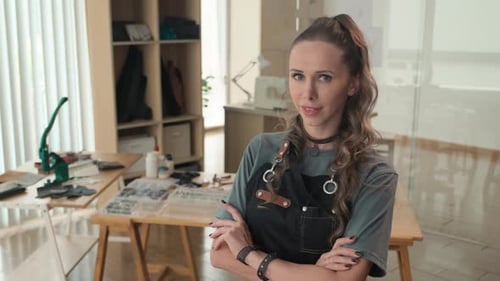 Cheerful Young Craftswoman Looking at Camera in Leather Workshop