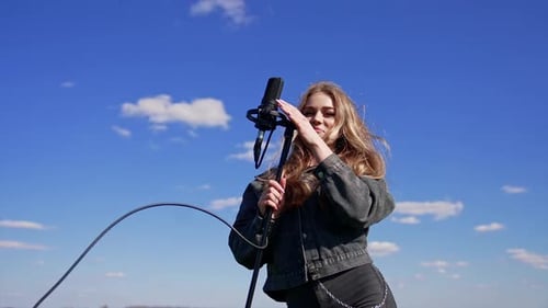 Young Woman Singing Outdoors Into Microphone on Sunny Day
