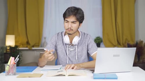 Student Studying at Table with Book and Laptop