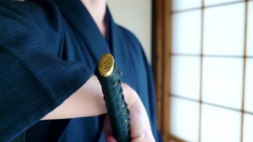 Ein Mann in einem traditionellen japanischen Kimono mit einem Katana-Schwert eines Samurai in einem alten traditionellen Japanisch