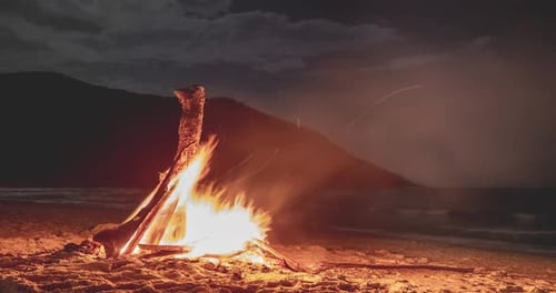 Lagerfeuer am Strand bei Nacht unter Mondlichtwolke Zeitraffer über der Bertinsel Burning Wood