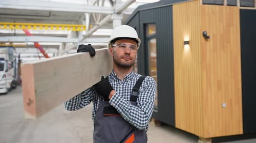 Construction Worker Carrying Wood in a Factory