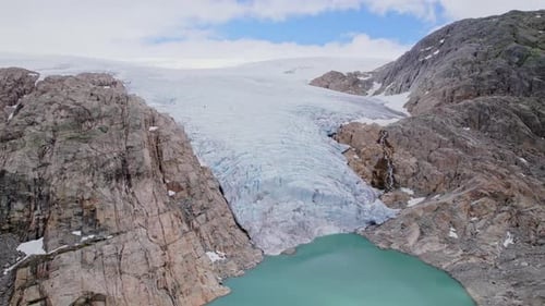 Aerial View Of Norwegian Glacier Surrounded By Rugged Rocky Terrain