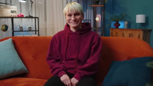 Smiling Young Adult Giving Thumbs Up on Couch