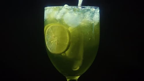 Stirring Lemonade in Glass Black Background Close Up Limes Spinning