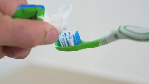 Close-up slow motion shot of toothpaste squeeze onto toothbrush dental gel cleaning personal hygiene