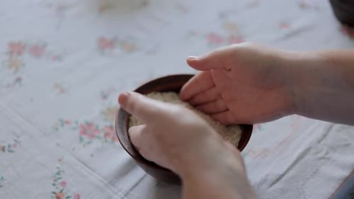 Hands Tossing White Rice in a Bowl