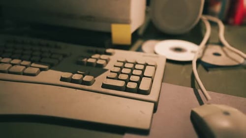 Dusty Computer Keyboard and Mouse on Cluttered Desk with CDs and Speakers