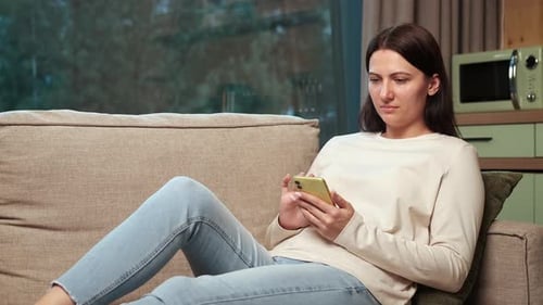 Woman Relaxing on Couch Using Smartphone