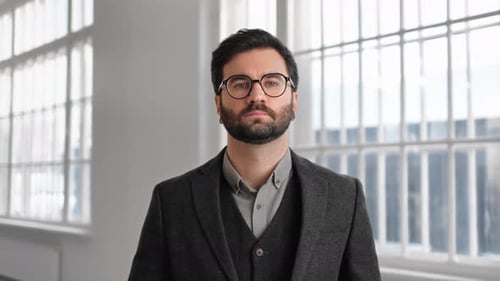 Portrait of Handsome Adult Man with Beard and Eyeglasses Dressed in Business Suit in Modern Building