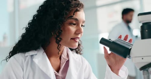 Woman Scientist Viewing Sample Through Microscope in Lab