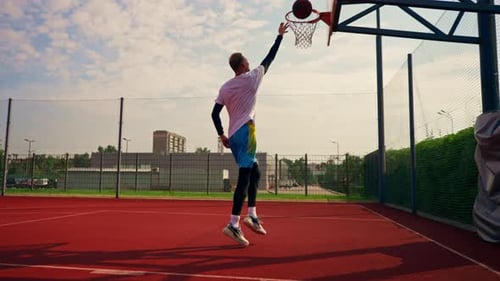 Ein großer Basketballspieler wirft auf einem Basketballplatz im Park einen Ball in einen Basketballkorb