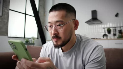 Smiling Man Texting Using Smartphone At Home Close Up