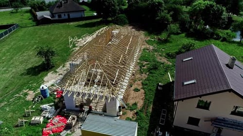 Aerial view of building a roof structure with wooden trusses.