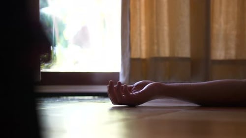 Scène inquiétante de la main d'une personne allongée sur le sol.