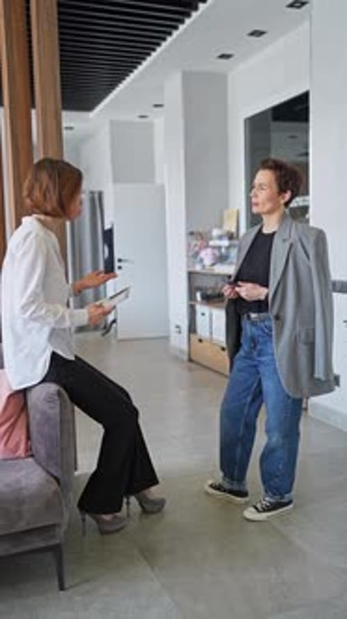 Membres féminins de l'équipe debout et parlant au bureau dans une équipe d'espace de travail collaboratif lumineuse