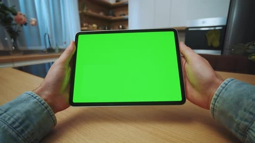 Hands Man Holding a Tablet Computer with a Horizontal Green Screen in the Kitchen Mockup Display