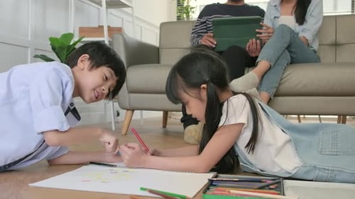 Children drawing on floor with parents on couch