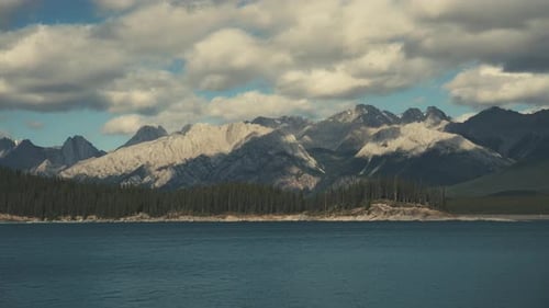 Timelapse of clouds moving above Rocky Mountains peaks and a blue lake