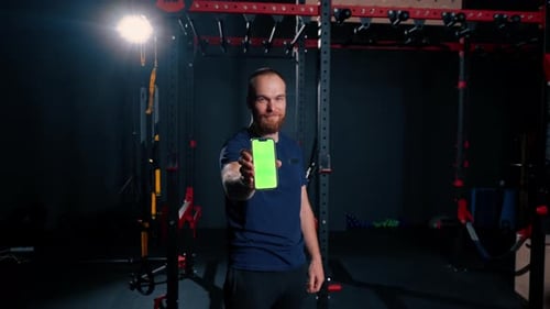 man fitness trainer shows phone with green screen sport lifestyle training technology